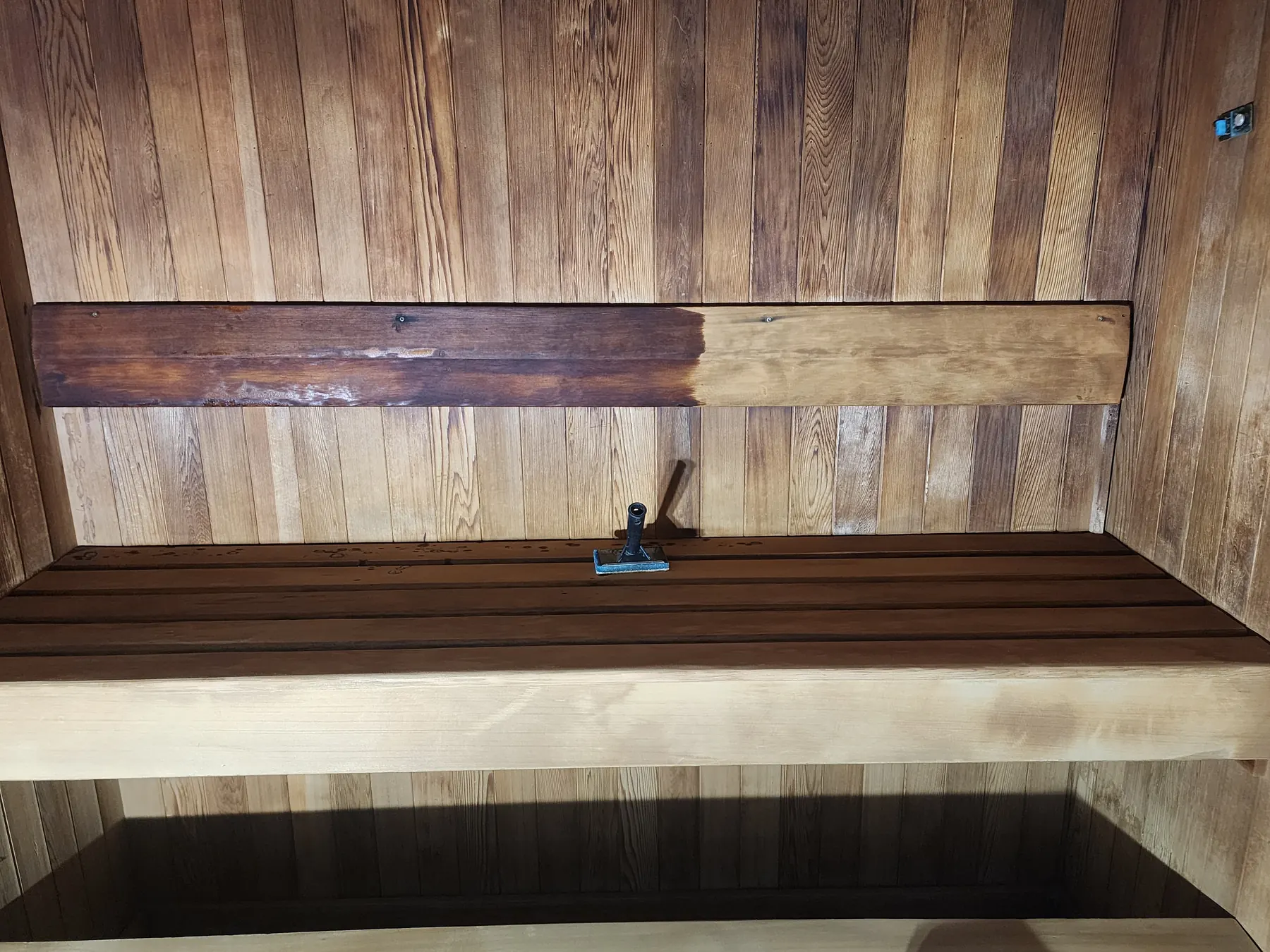 Sauna backrest half sanded, showing old worn timber next to fresh, clean wood