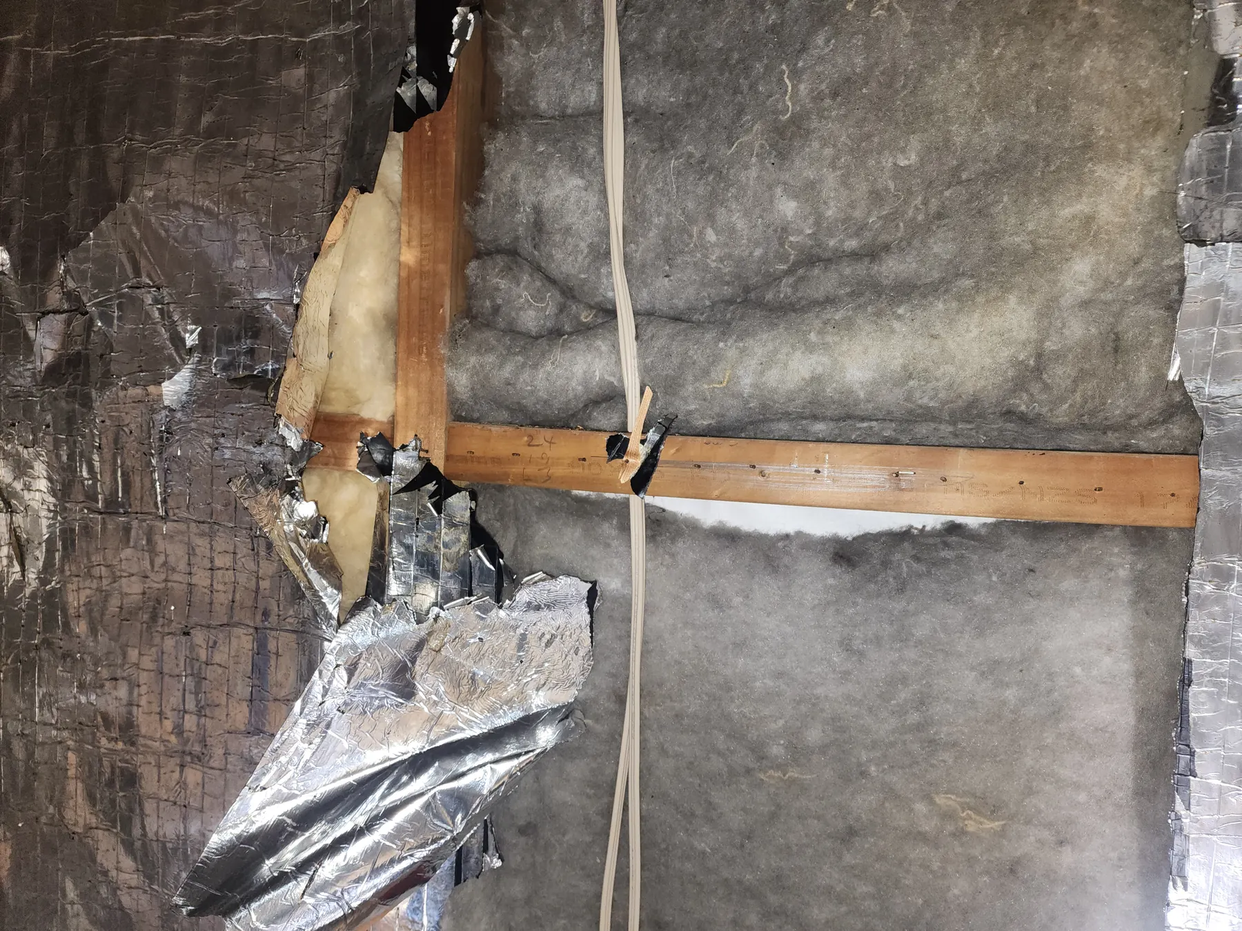 Torn foil and insulation around the framing