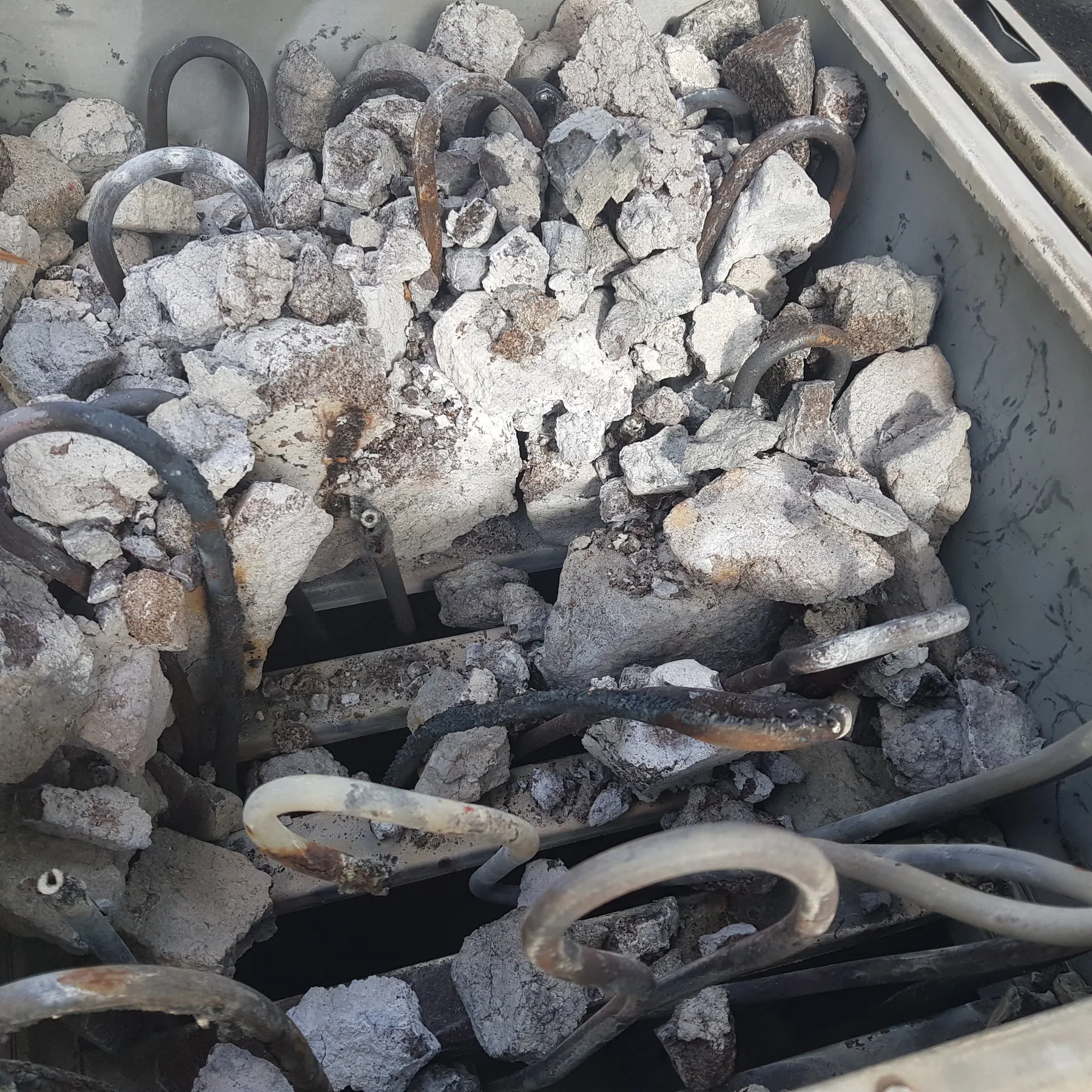 Crumbled, worn-out sauna stones packed around burnt heater elements