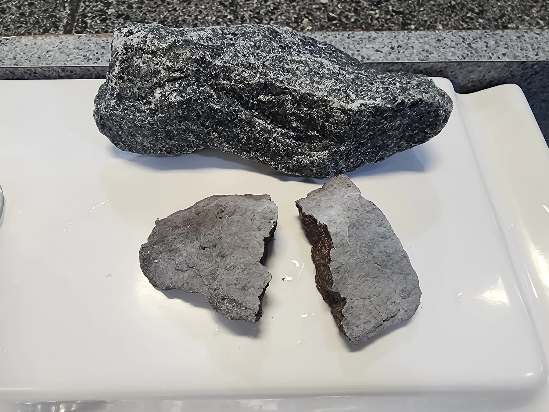 A fresh sauna stone next to an old one that has split in two